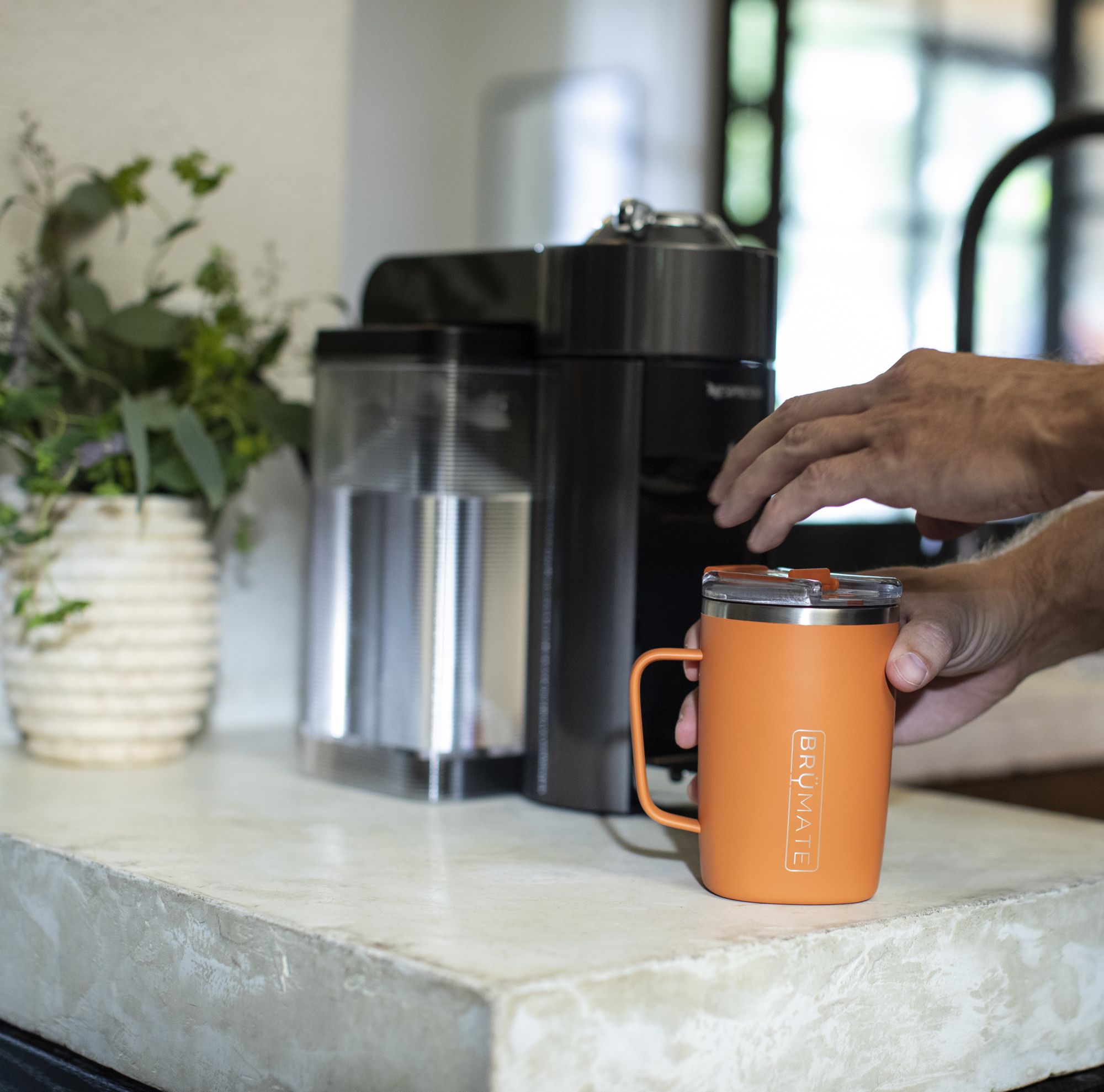 A man getting coffee in an orange mug. 