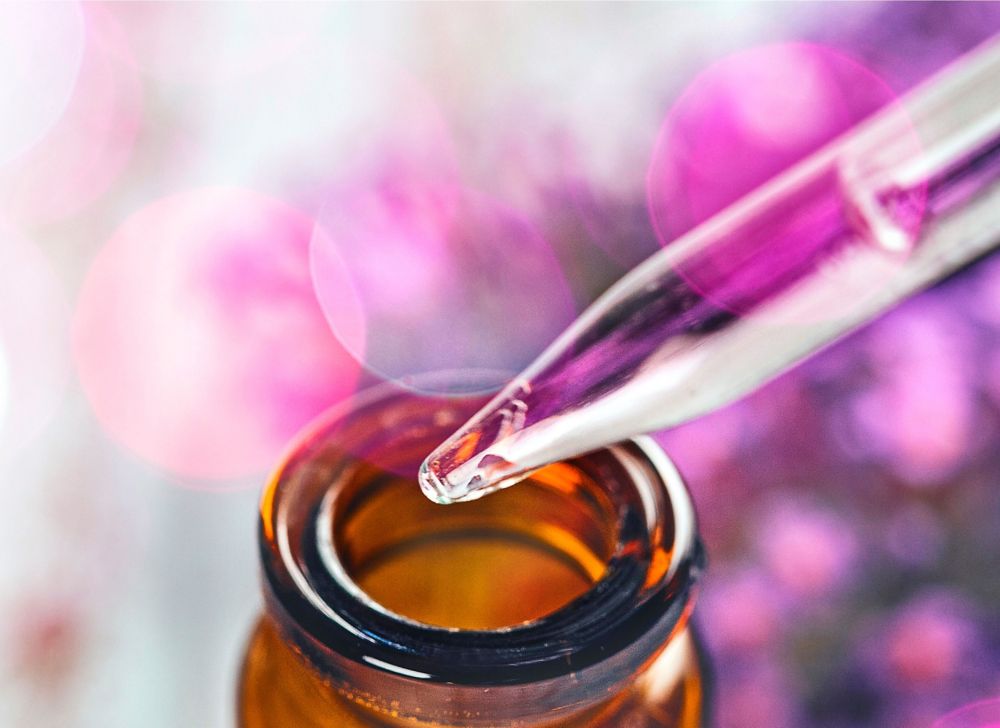 Clear liquid drips from a dropper into an amber vial. 