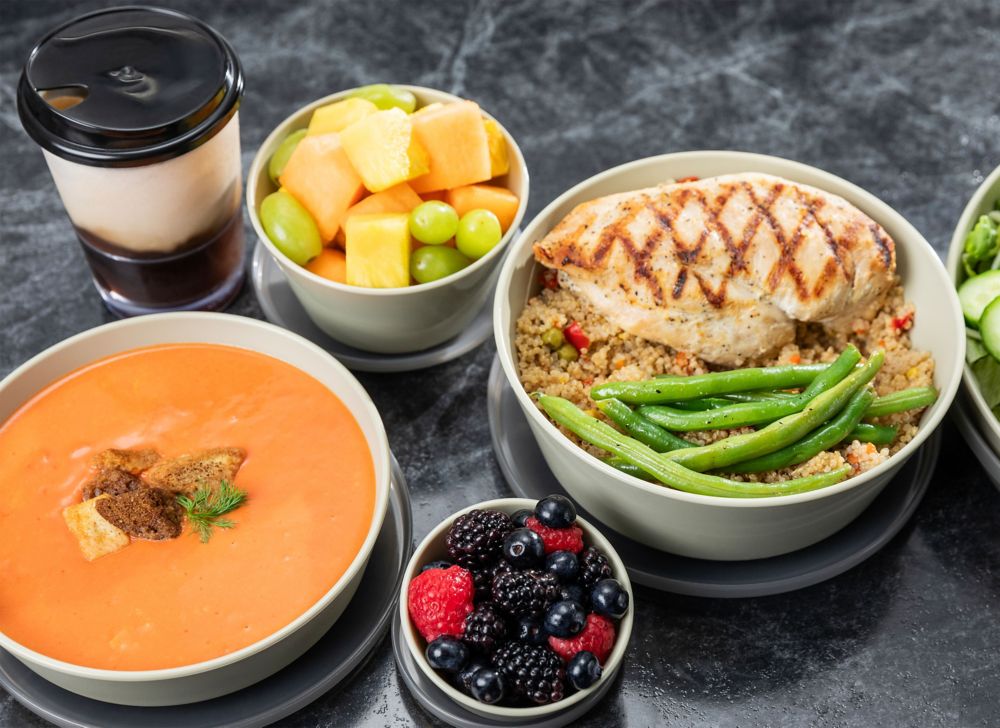 Reusable serveware containers are filled with an array of food and drink. 