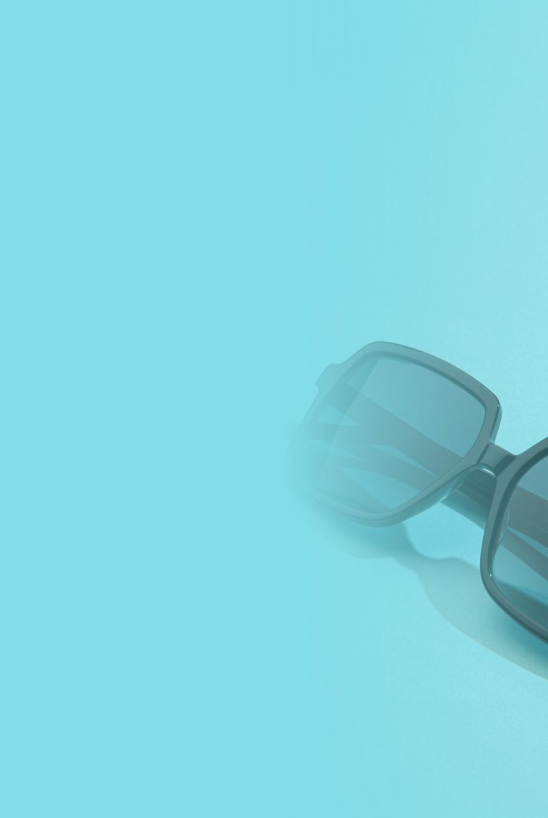 Black sunglasses rest on a light blue surface. 