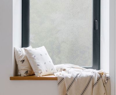 Cozy, private window nook showing the installed crackled glass film behind throw pillows.