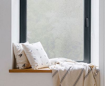 Cozy, private window nook showing the installed crackled glass film behind throw pillows.