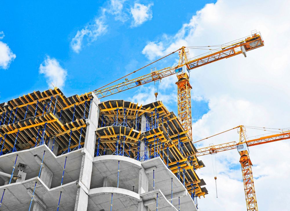 Cranes rise over a building that’s under construction. 