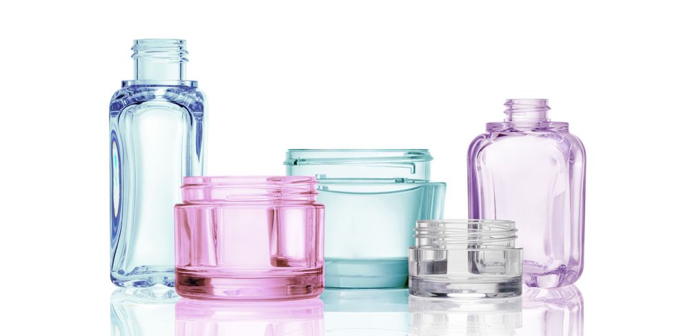 A row of clear, colorful cosmetic jars and containers made from Eastman Cristal One.   