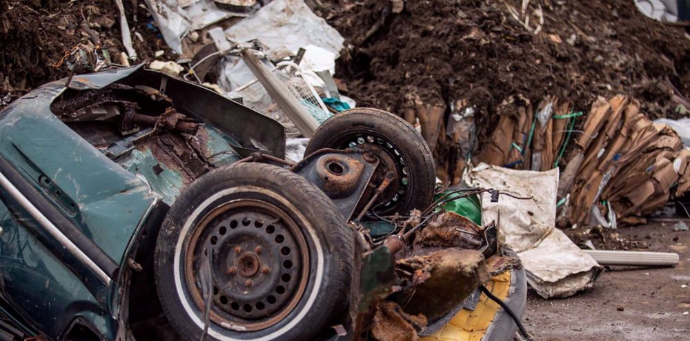 Crushed car with wheels facing up and its seat fibers spilling on the ground. 