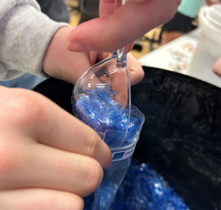 High school students fill a sample bag with blue plastic flakes. 