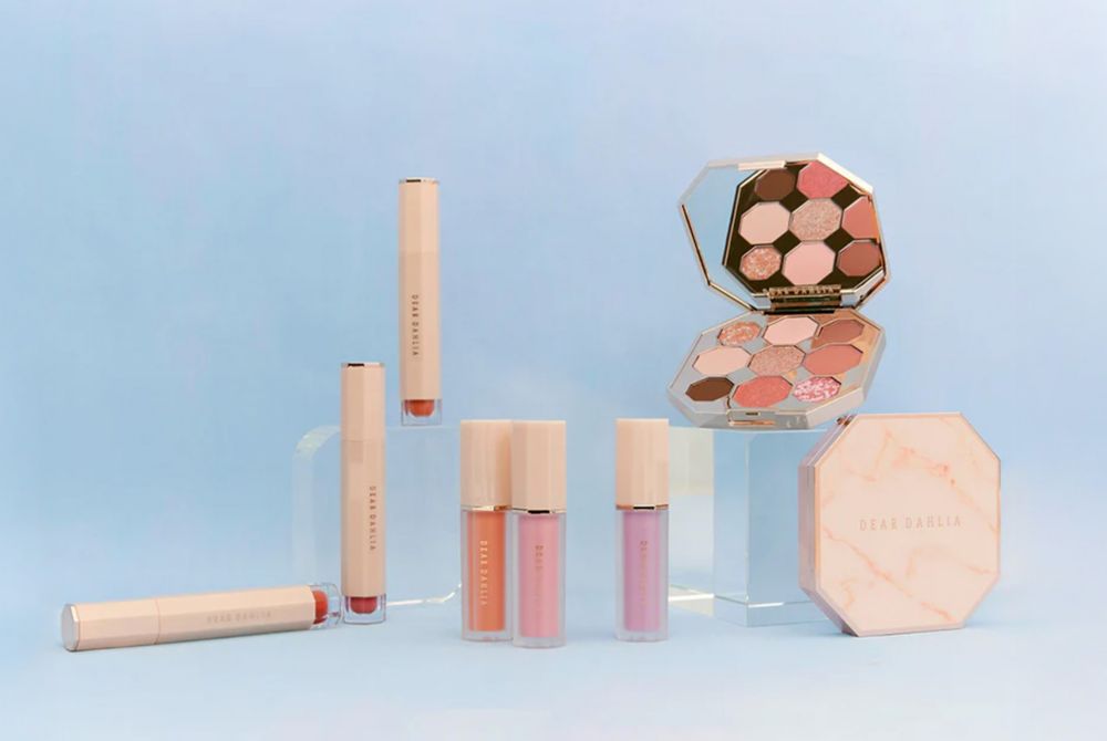 A makeup display of Dear Dahlia cosmetics, including eyeshadow palettes and lip gloss. 