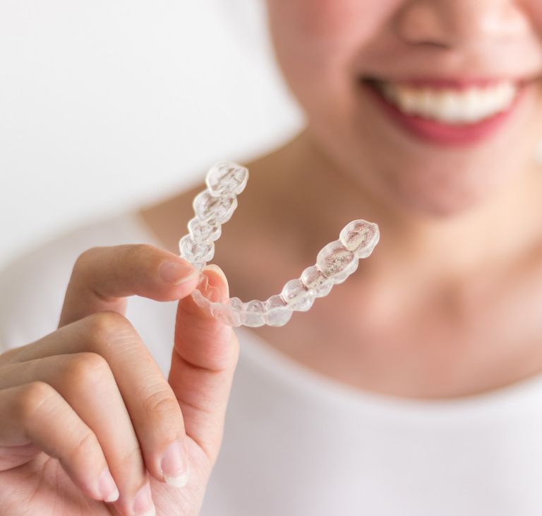 Close-up of a person holding dental aligners. 