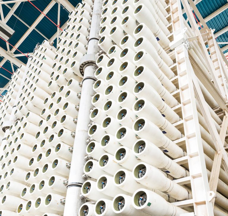 A large wall of white pipes with vales at the end of them 