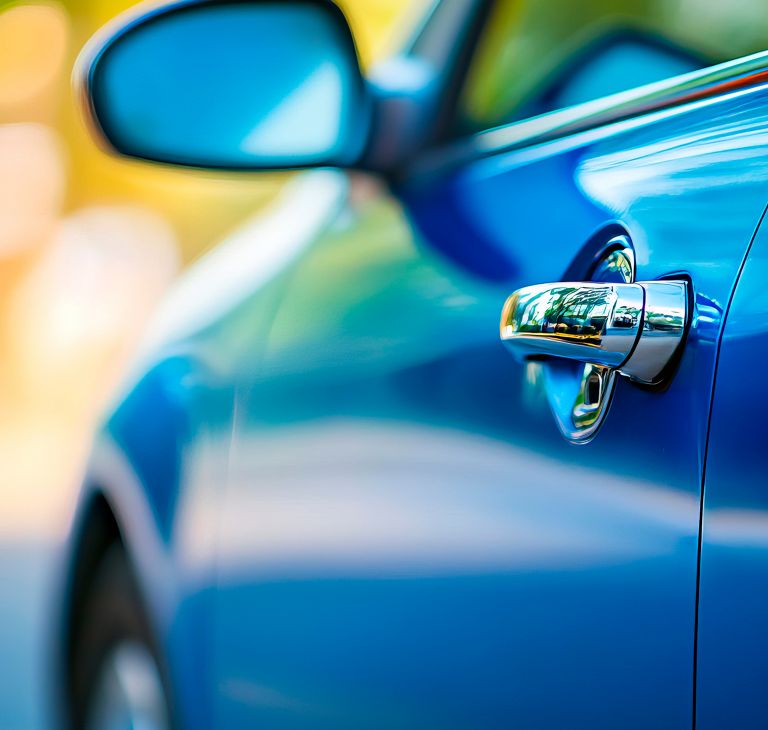 Close-up of blue car door handle and lock mechanism. 