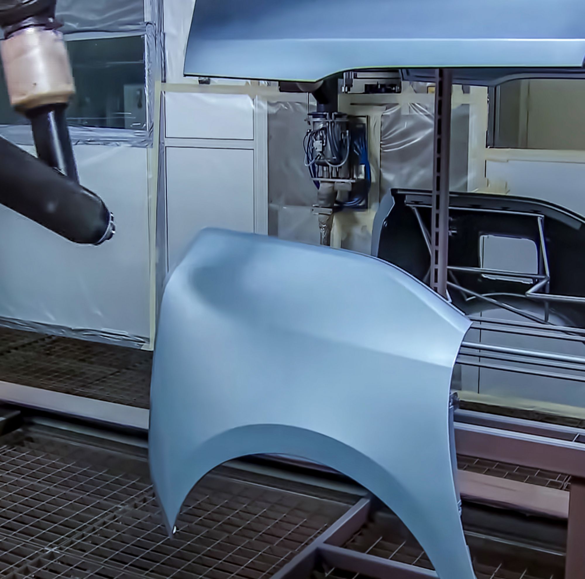 A machine primes a car body part. 