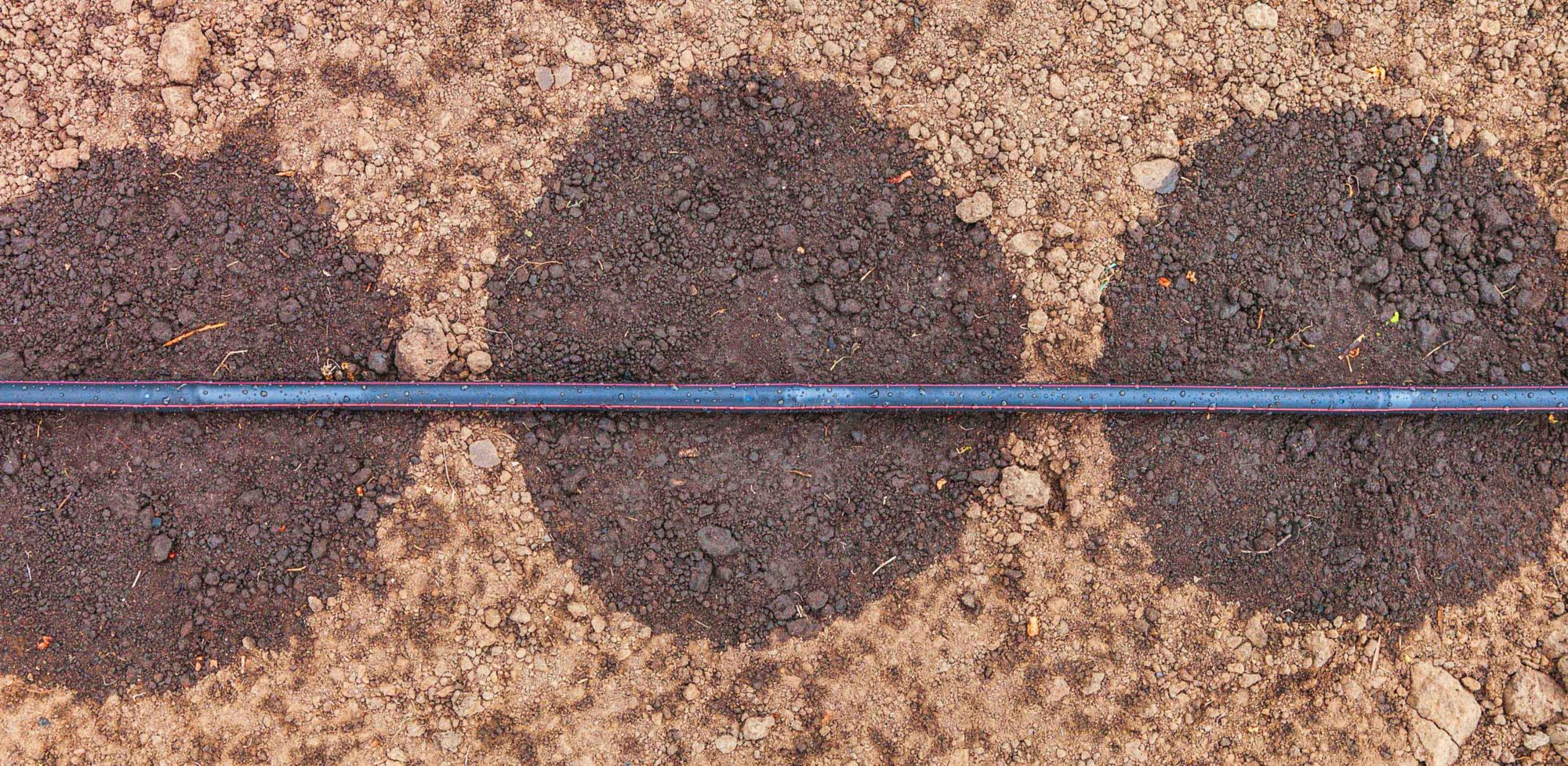 A top view of drip irrigation system watering dry soil 