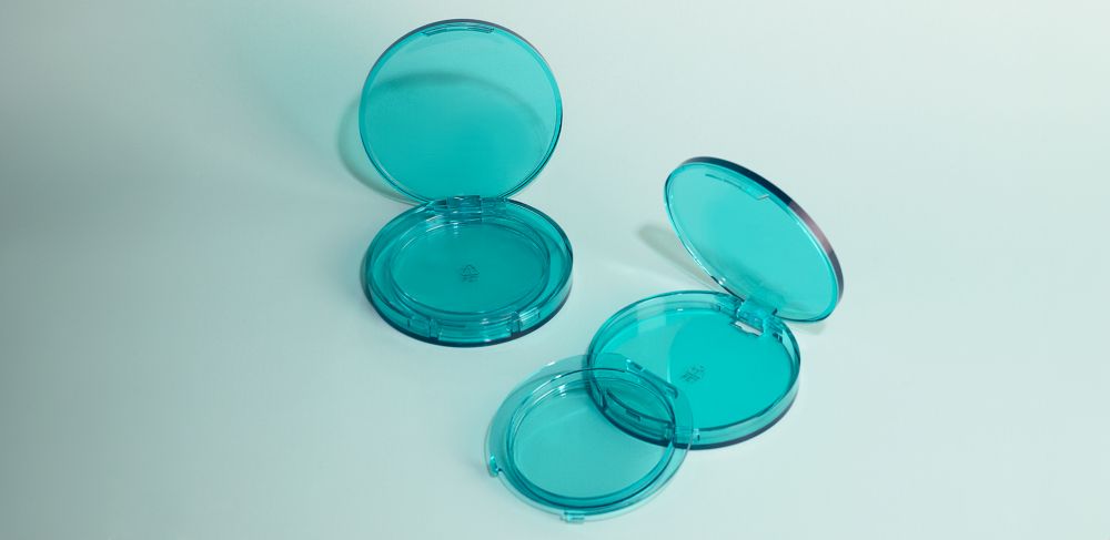 Two opened transparent teal compacts made of Eastman Cristal One Renew. 