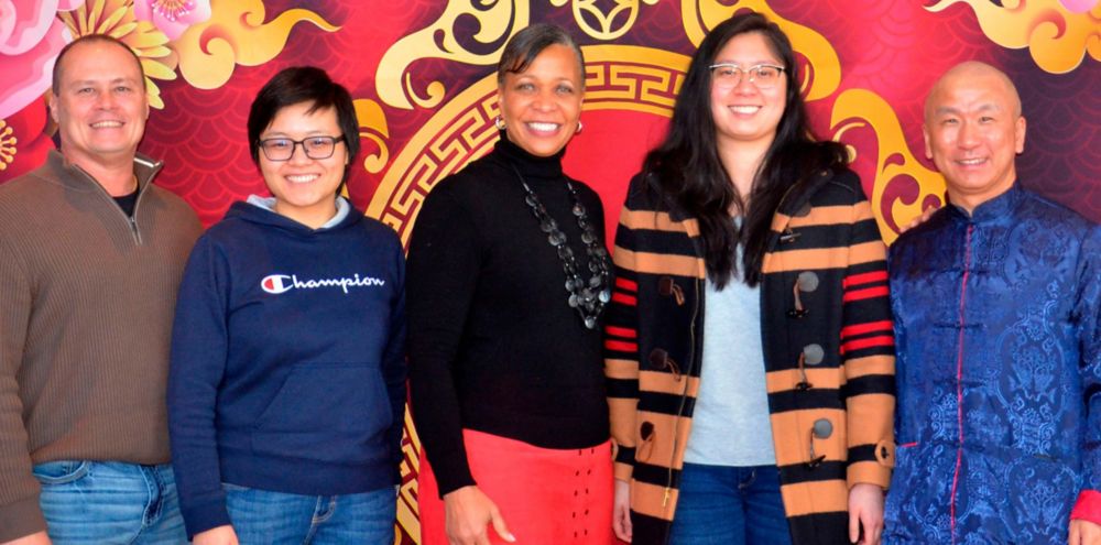Eastman employees, Jim Ziegler, Lin Feng, Kellye Walker, Stephanie Yeap, Sen Li, smiling in front of lunar new year backdrop. 