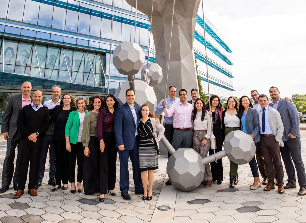 Un grupo de empleados de Eastman sonríen frente a Old Hand, una escultura de acero inoxidable en Kingsport, Tennessee. 