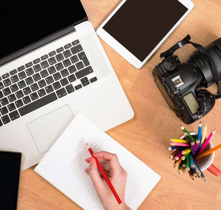 A laptop, tablet and digital camera displayed on a table. 