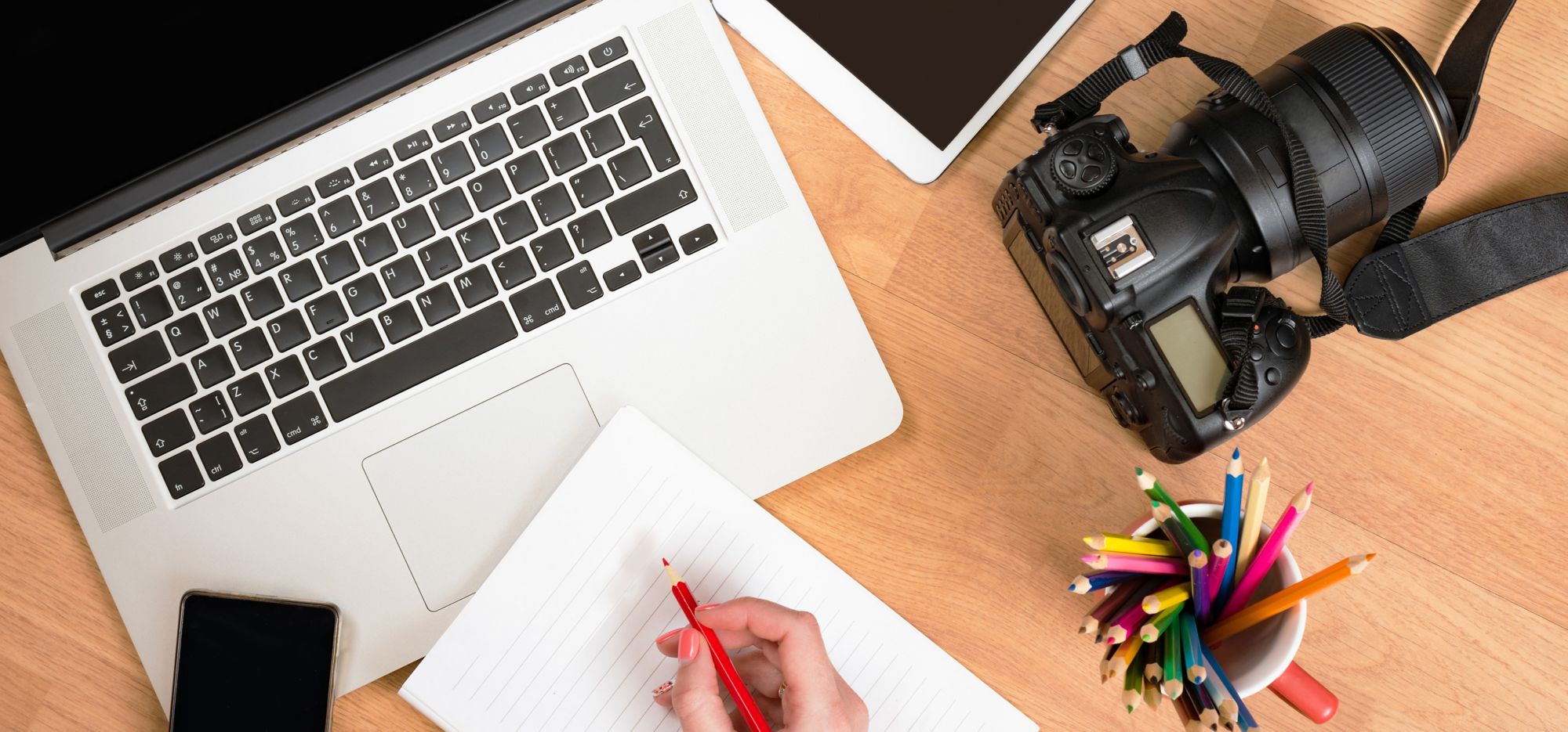 A laptop, tablet and digital camera on a table. 
