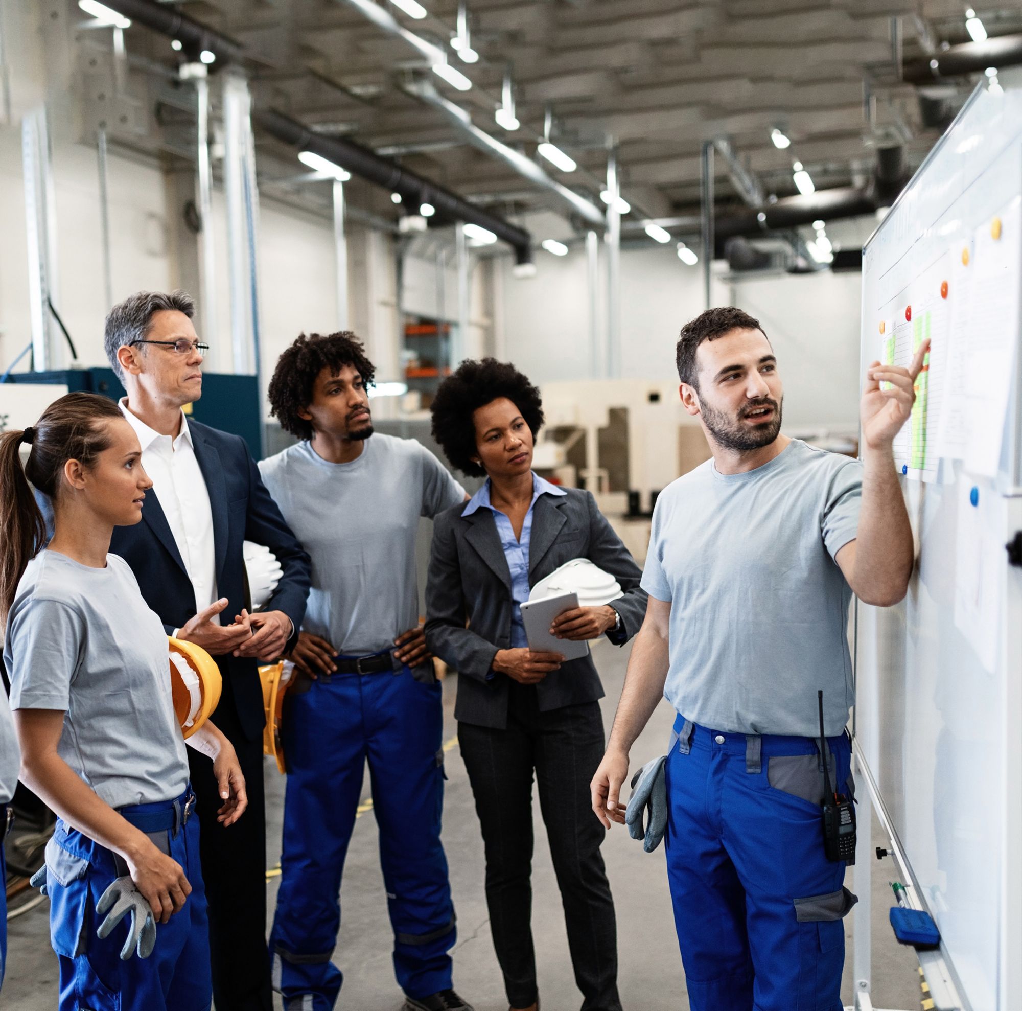 Engineers gather in front of a whiteboard to discuss plans. 