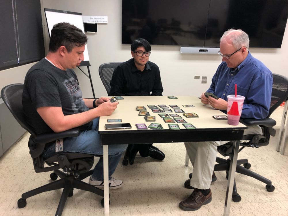 Three Eastman people playing dominion board game 