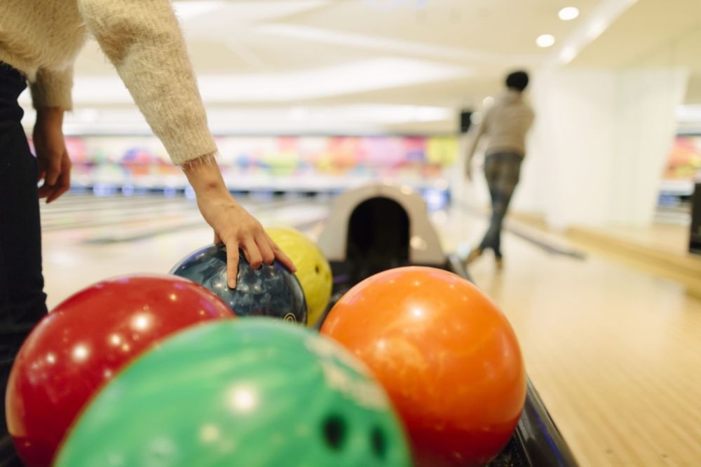 A man holding a bowling ball is about to throw it on a bowling lane. 