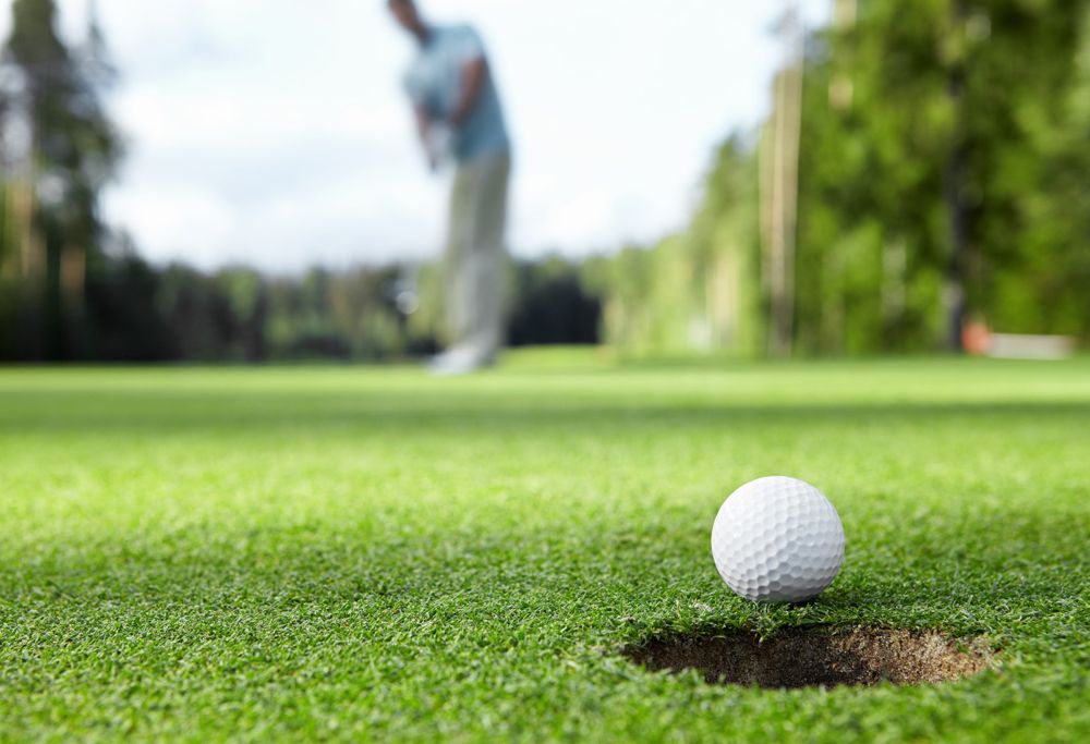 A golf ball on the green right next to the hole. 