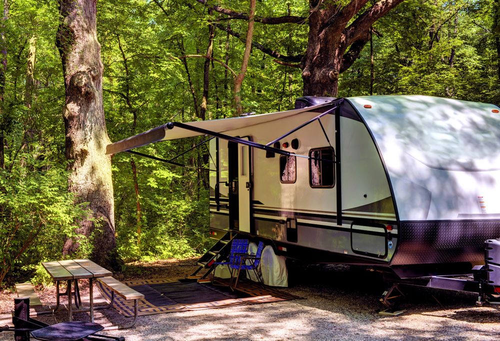 A travel trailer set up at a campsite in the forest. 