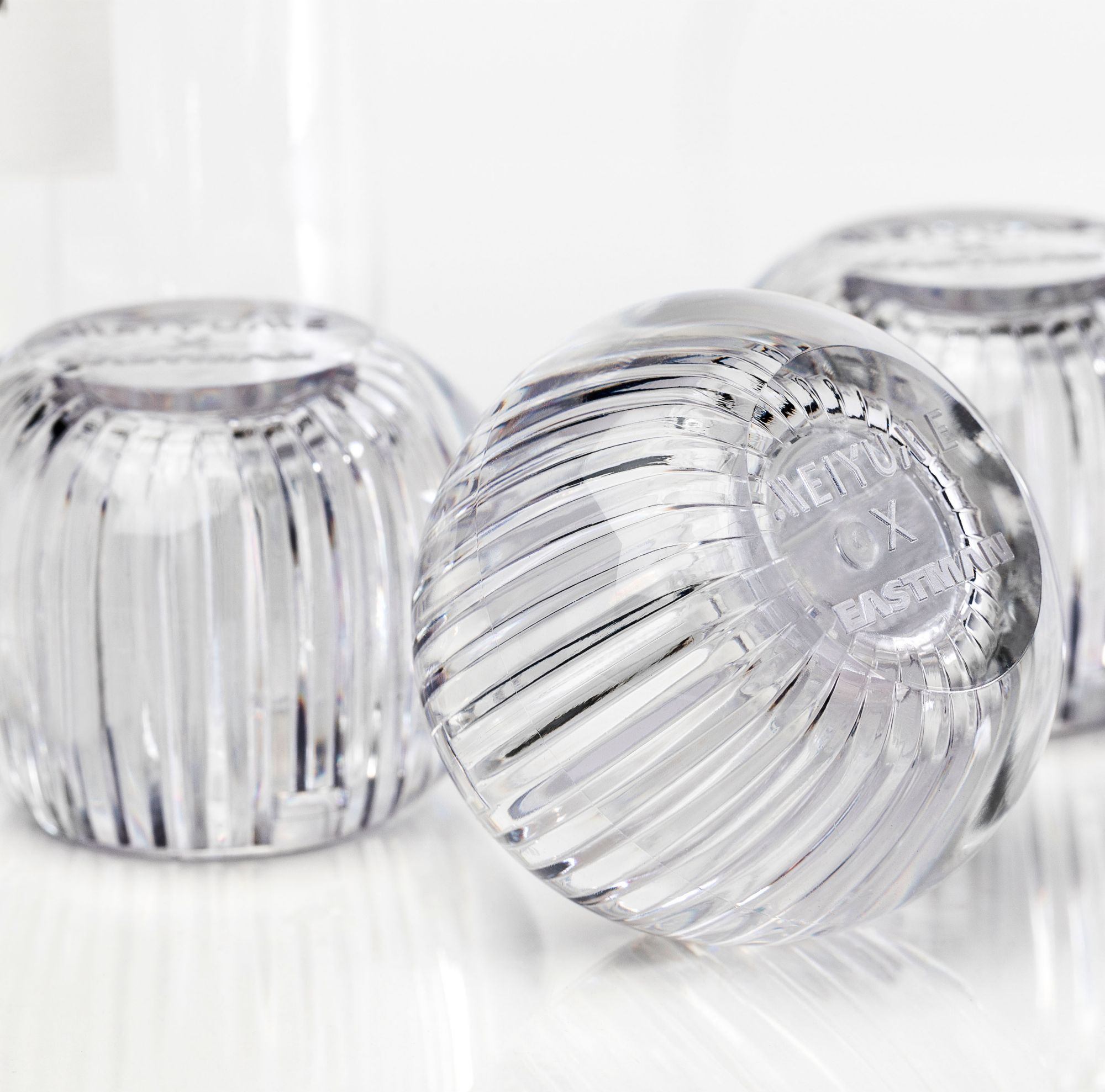 Two clear, faceted fragrance caps with clear, ribbed designs made fomr Eastman Cristal. 