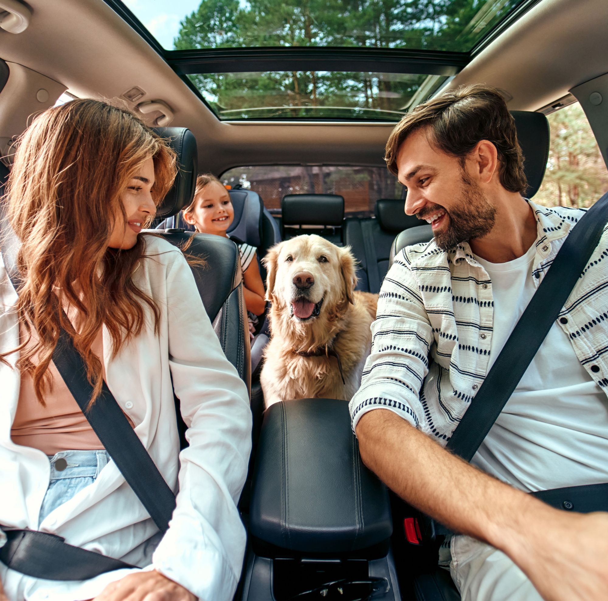 Two parents, their child and a golden retriever in a car. 