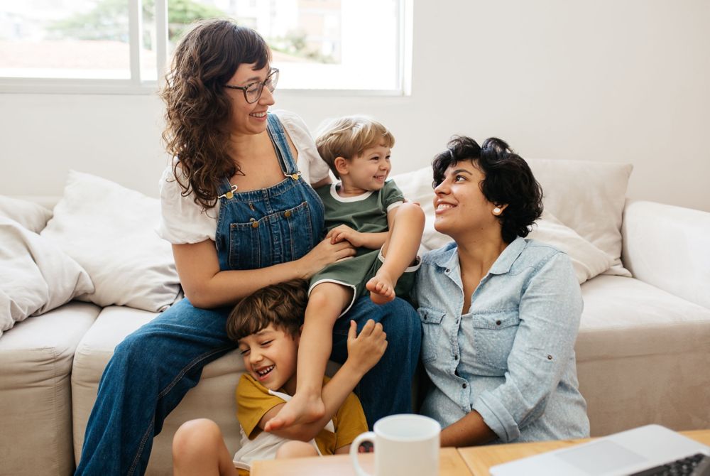 Family of four smiling at each other. 