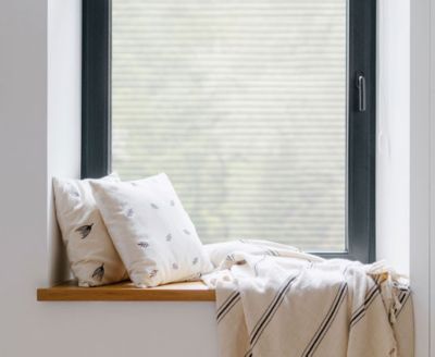Cozy, private window nook showing the installed Faux Blinds film behind throw pillows.