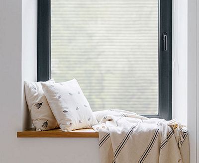 Cozy, private window nook showing the installed Faux Blinds film behind throw pillows.