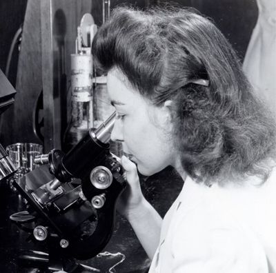 Female lab worker looking through microscope