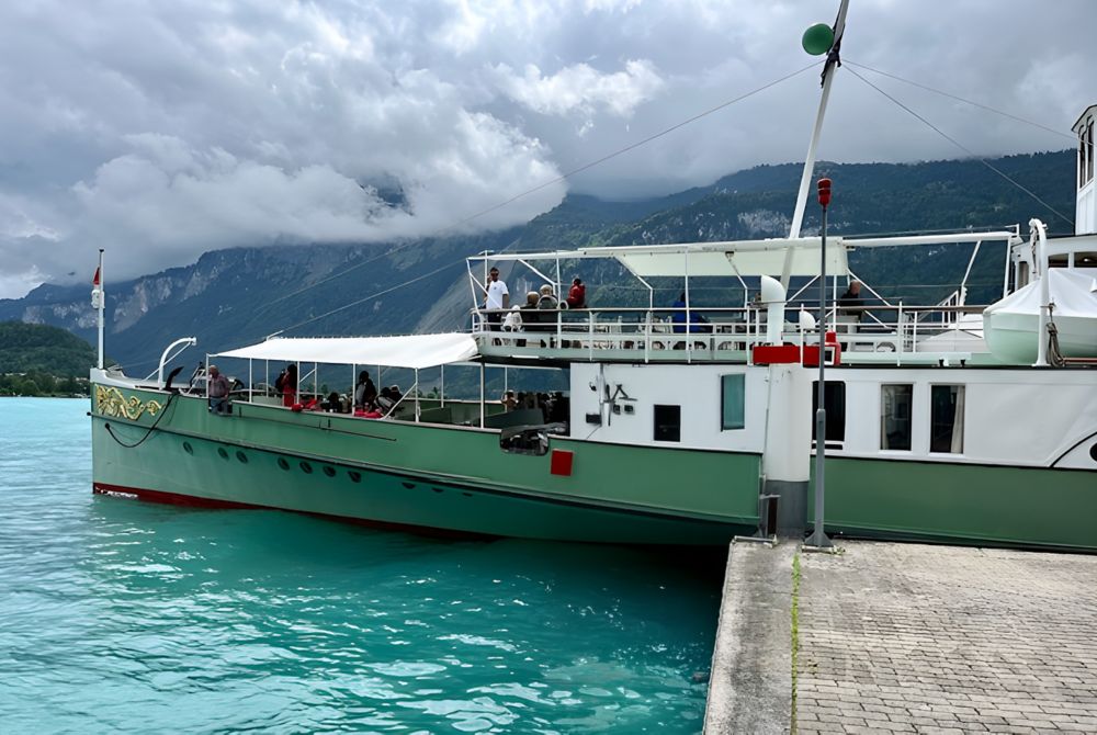 A ferryboat floats at the dock with Swiss mountains in the background.  