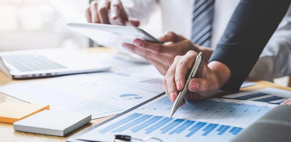 A person uses pen to point at a graph on a clipboard. 