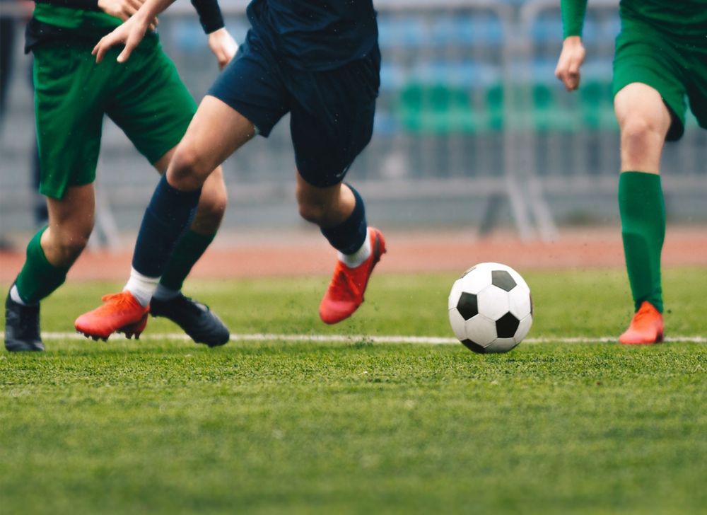 Football players kicking the ball on artificial turf 