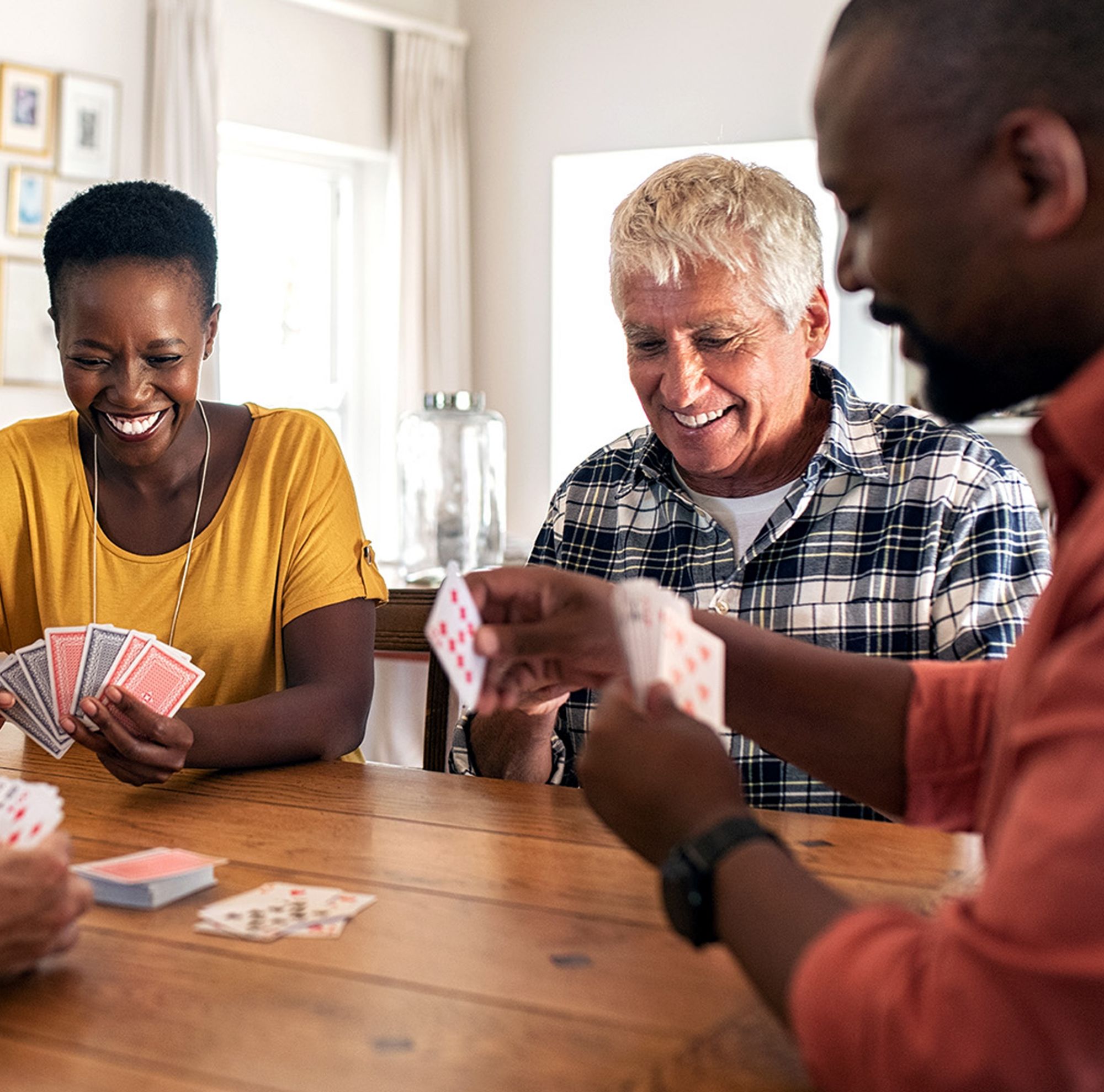 Four friends smiling as they play card games. 