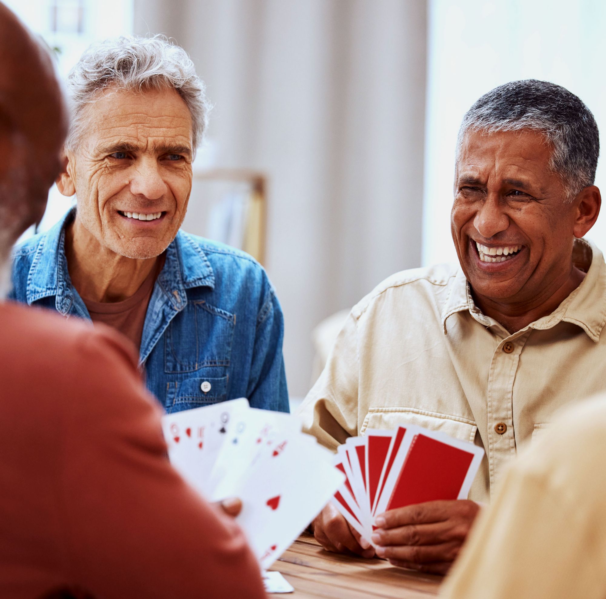 Two men smile while playing a card game. 