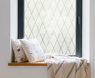 Cozy, private window nook showing the installed Frosted Lattice film behind throw pillows.