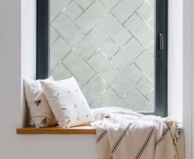 Cozy, private window nook showing the installed Frosted Tiles film behind throw pillows.