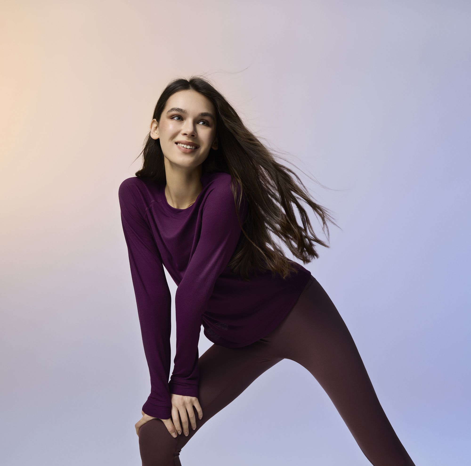 A person in leggings and a loose long-sleeve shirt stretches. 