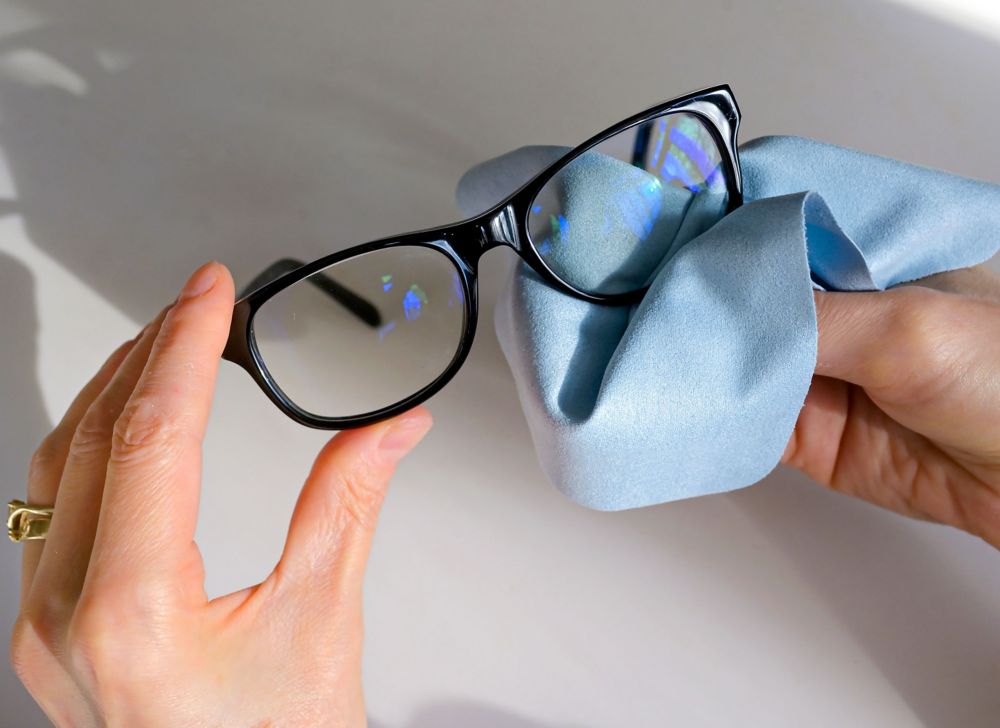A person cleaning glass lenses with microfiber cloth. 