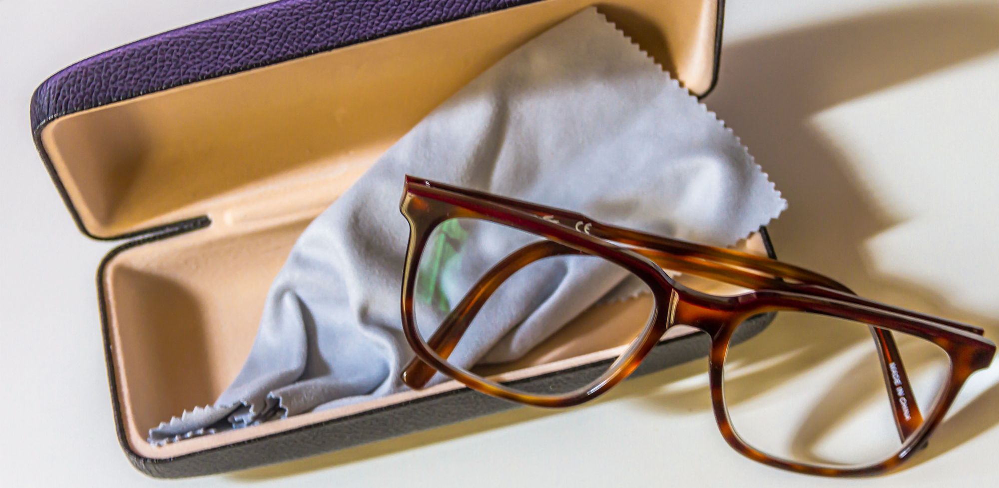 Tortoiseshell acetate eyeglasses lay partially in a case. 