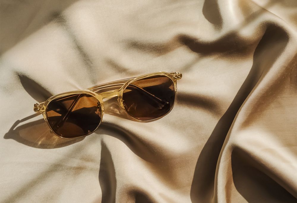 A pair of sunglasses resting on cream-colored cloth. 