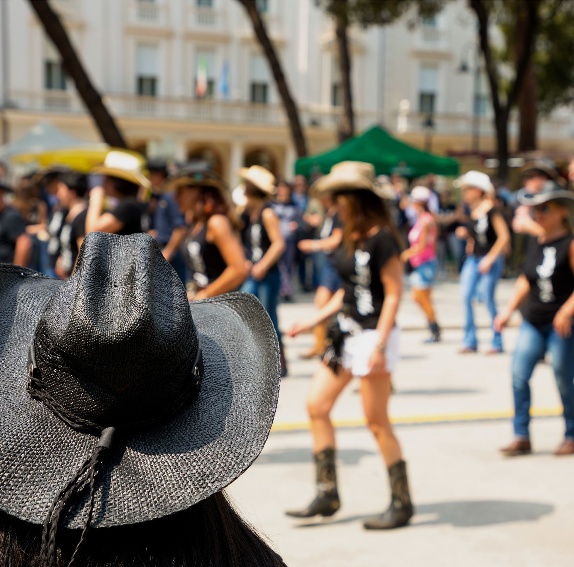 Dancers wearing hats and boots dancing in a public space. 