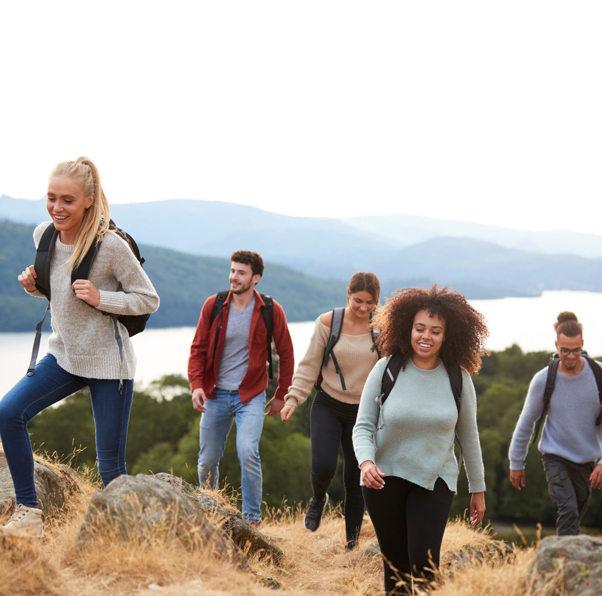 Five university students wear backpacks as they hike up a mountain. 