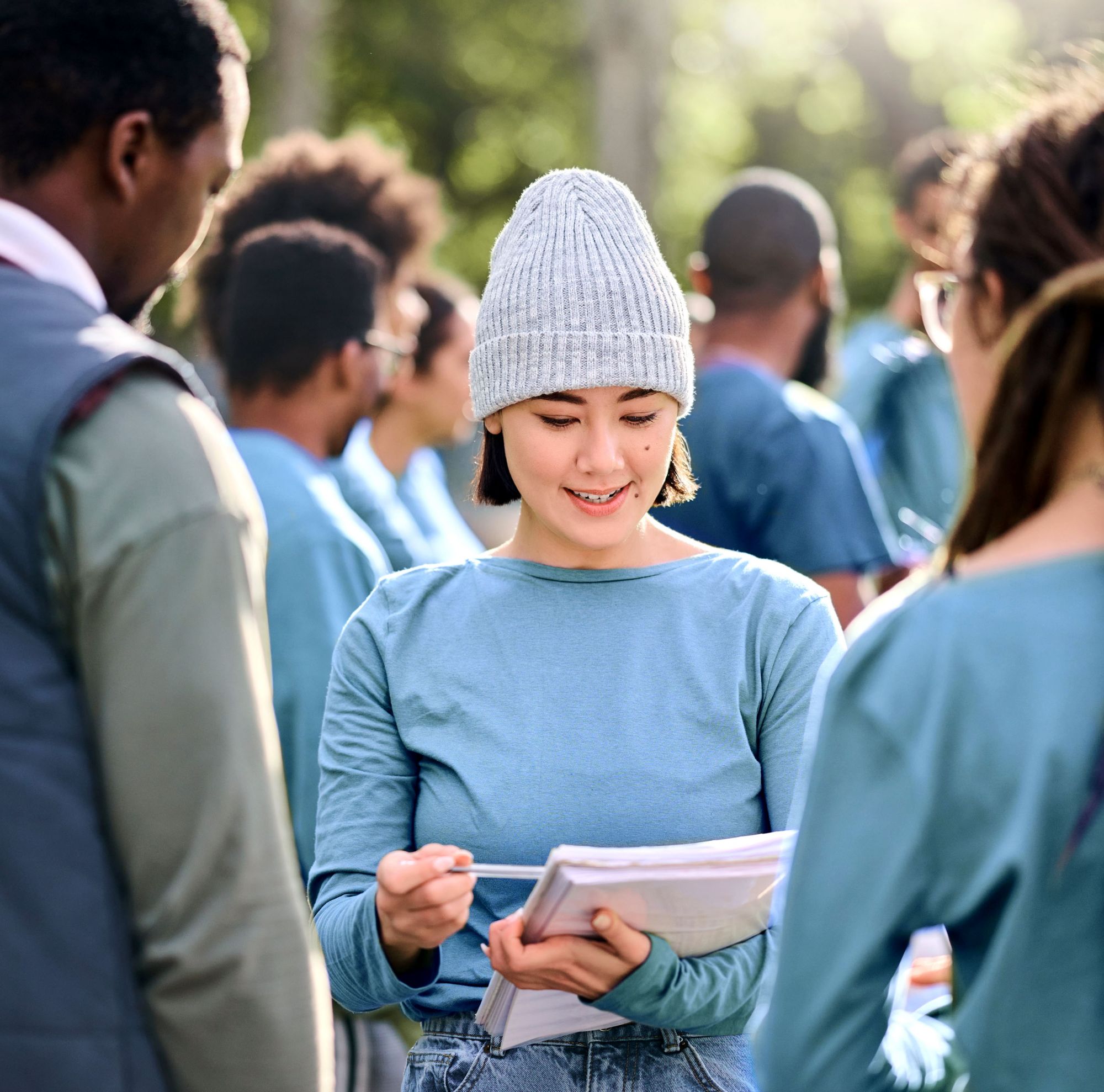 Female wearing a beanie volunteering outdoors with others. 