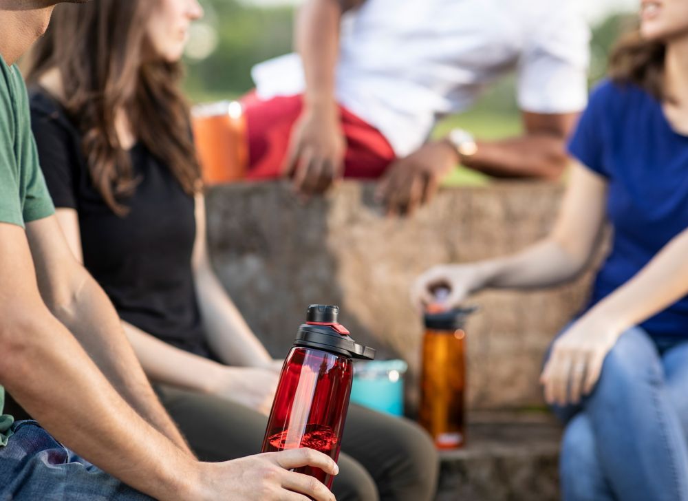People sit together and hold reusable water bottles made with Tritan. 