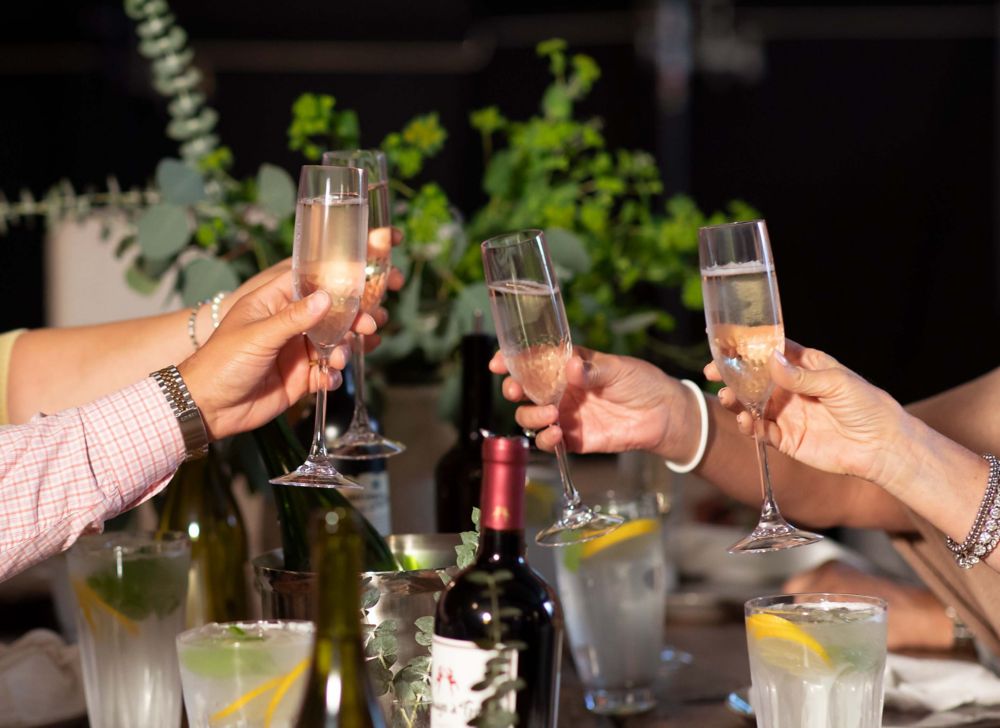 A group toasting with clear glasses filled with champagne. 
