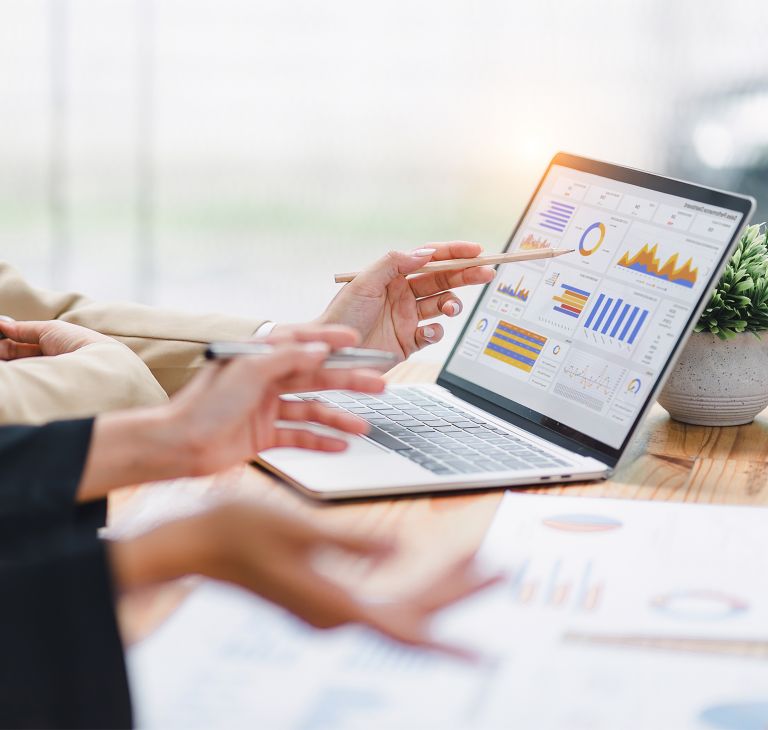Employees discuss performance data displayed on a laptop.  