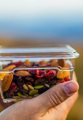A person holds up a container of trail mix.